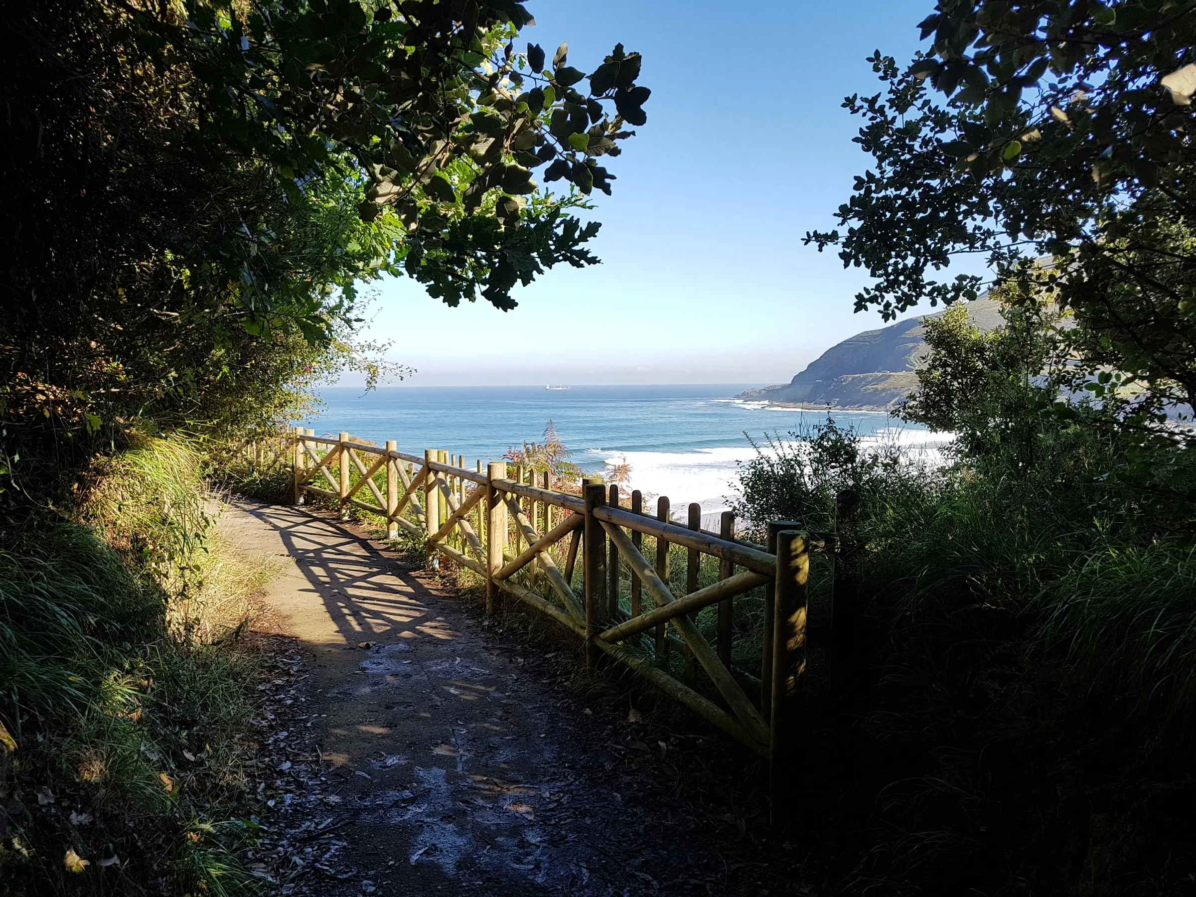 Sendero con barandilla de madera junto al mar en Cobarón